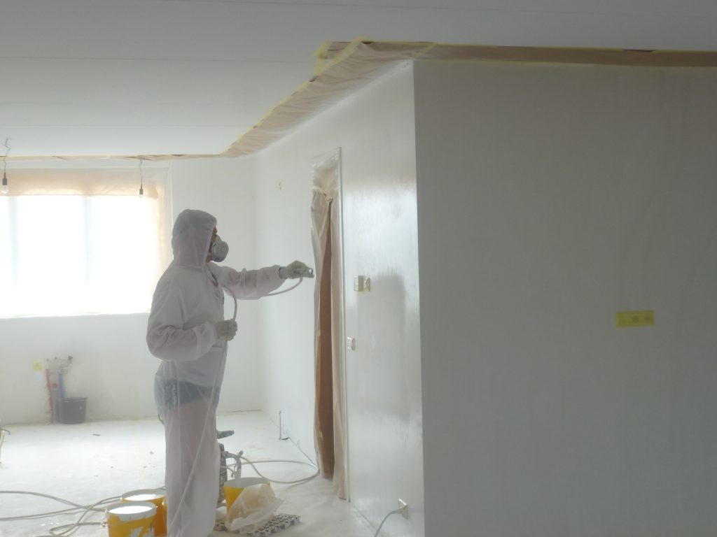 Latexspuiter aan het werk met airless verfspuit voor gladde muren in Amsterdamse woning
